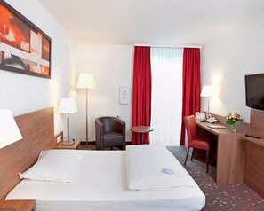 A hotel room with a bed, two bedside tables with lamps, a desk with a chair, a television, and a window with red curtains. - Best Western Hotel Erlangen (Erlangen)