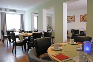 A hotel dining area with multiple tables and chairs, a large window with curtains, and artwork on the walls. - Best Western Hotel Erlangen (Erlangen)