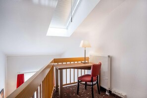 A small, well-lit room with a wooden desk, a red chair, a lamp, and a radiator. - Best Western Hotel Erlangen (Erlangen)