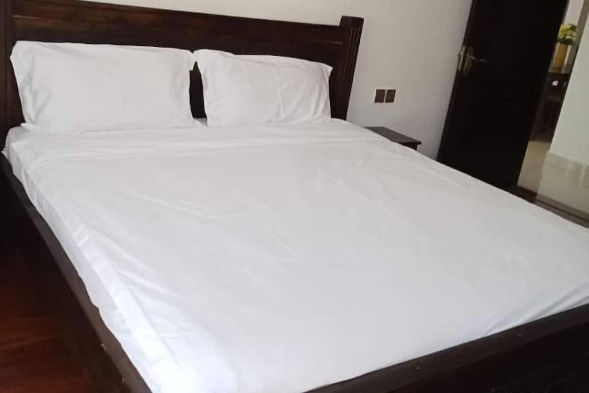 A neatly made bed with white linens in a room with a dark wooden headboard.