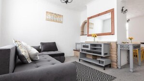 Un salon moderne avec un canapé gris, une console en bois et un grand miroir.