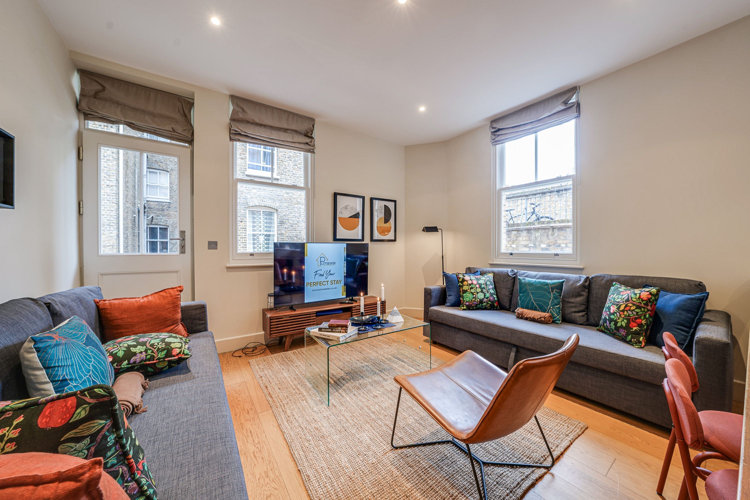 Ein Wohnzimmer mit Sofa, Sessel, Couchtisch und Fernseher.