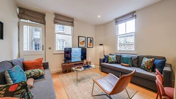 A living room with a sofa, armchair, coffee table, and a television.
