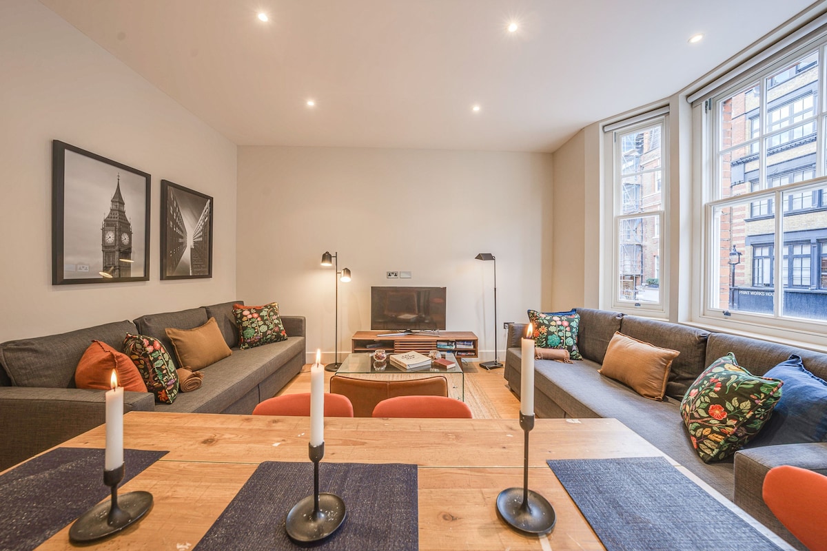 Een moderne woonkamer met een bank, een bijzettafeltje en twee kaarsen.