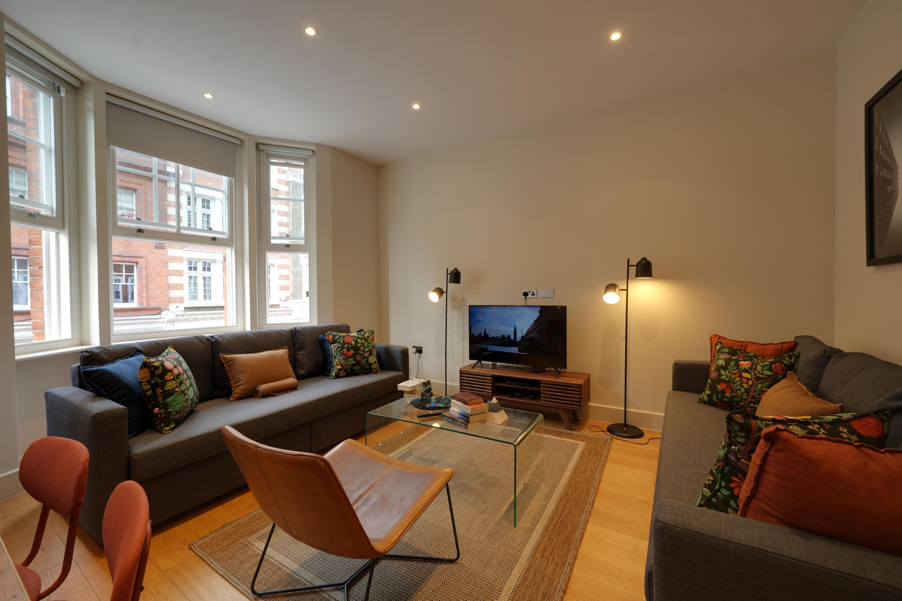 A modern living room with a sofa, armchairs, a coffee table, and a TV.
