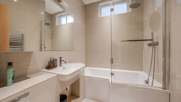 A modern bathroom with a glass-enclosed shower, a standalone bathtub, and a vanity with a sink.