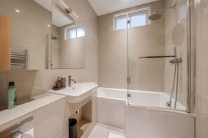 Een moderne badkamer met een douchecabine van glas, een vrijstaand bad en een wastafelmeubel met een wastafel.