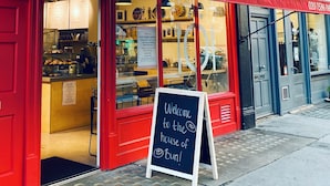 Une devanture rouge avec une enseigne indiquant « ScandiKitchen.co.uk » et un panneau noir à l’extérieur accueillant les visiteurs à la maison de Bun.