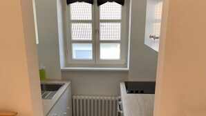 Une petite cuisine avec une fenêtre, un radiateur et un évier.