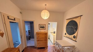 Une cuisine compacte avec un meuble en bois, une table à manger avec des chaises, un luminaire suspendu et une affiche accrochée au mur.