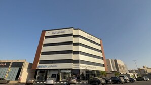 A multi-story building with commercial signage on the ground floor. - Lamar Park Hotel Al Rayan (Tabuk)