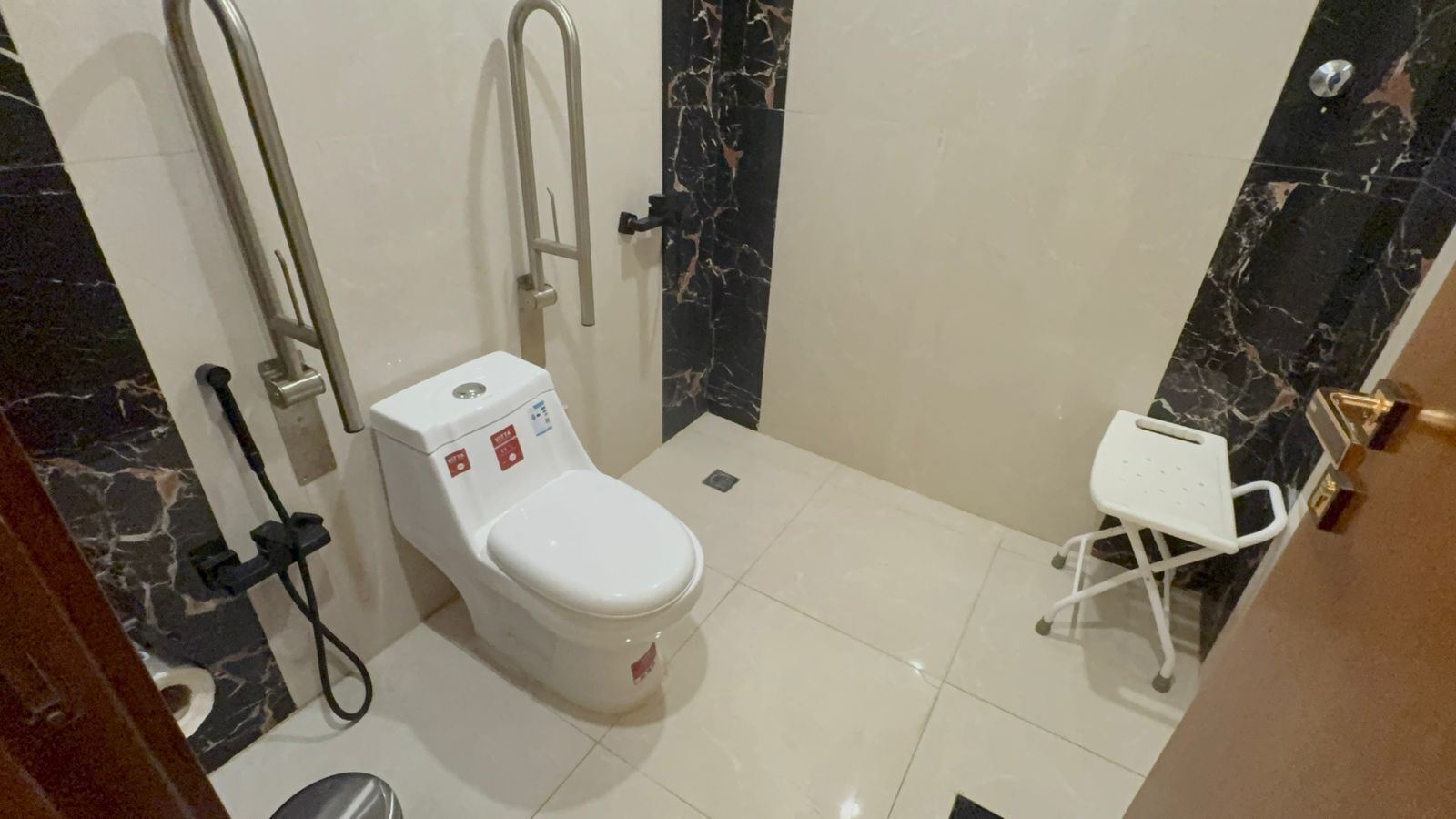 Un baño con inodoro, ducha y una pequeña silla blanca.
