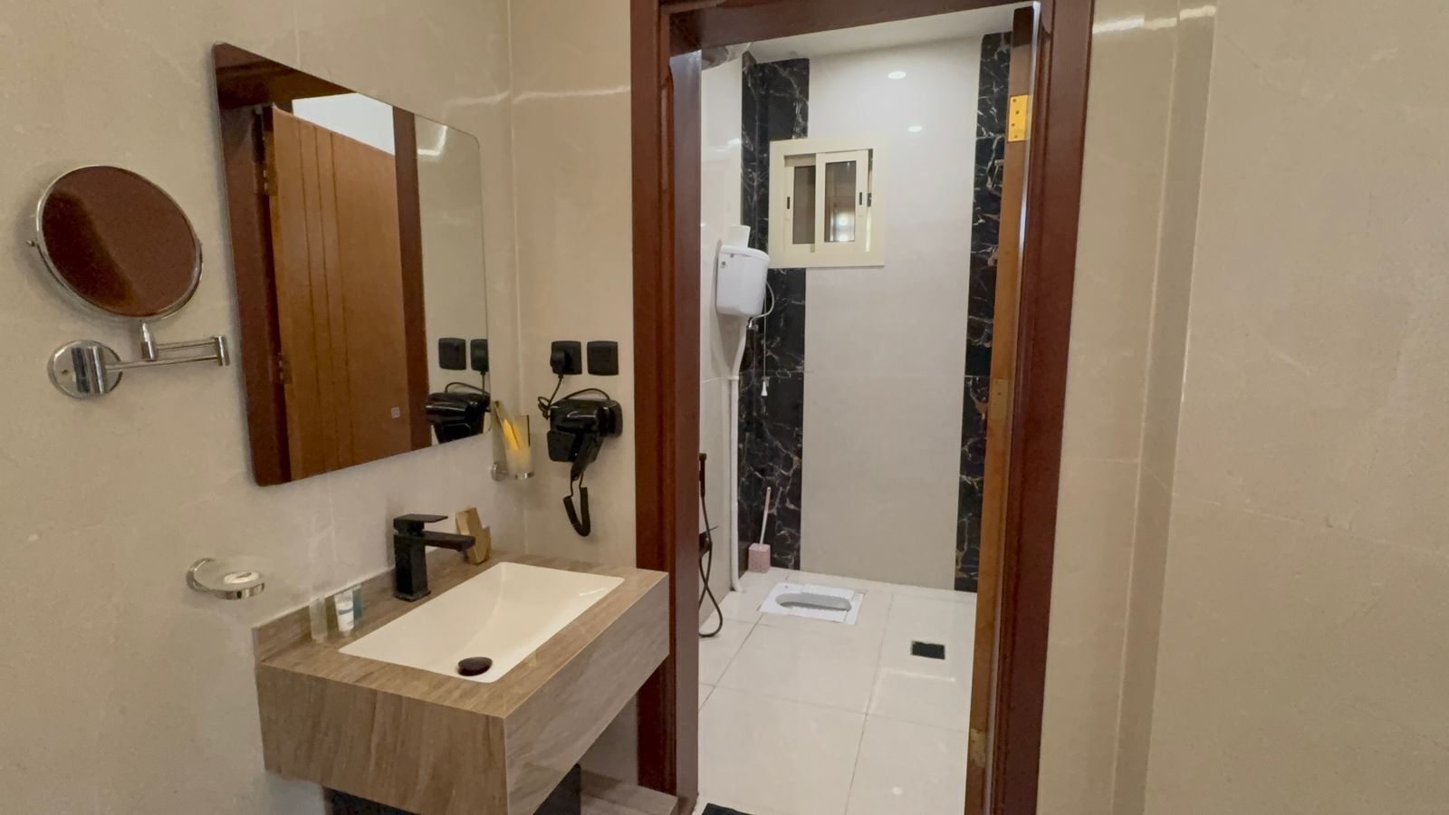 Une salle de bain moderne équipée d’un meuble-lavabo, d’un miroir, d’un sèche-cheveux et d’un espace douche.