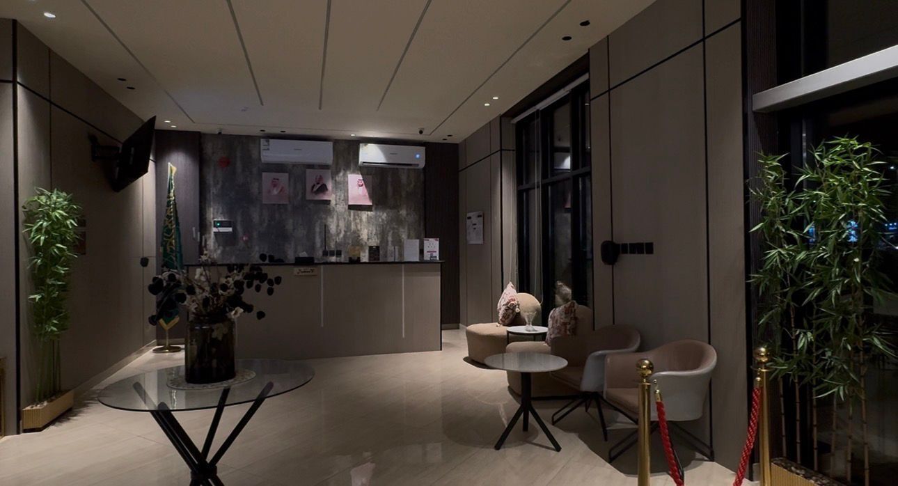 A modern lobby with a reception desk, seating area, and decorative plants.