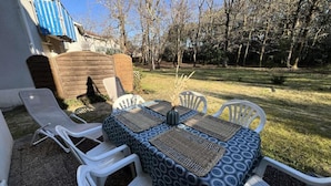 A patio with a table and chairs, a wooden fence, and a grassy yard. - House in Soulac-sur-mer Near Beach (Soulac-sur-Mer)