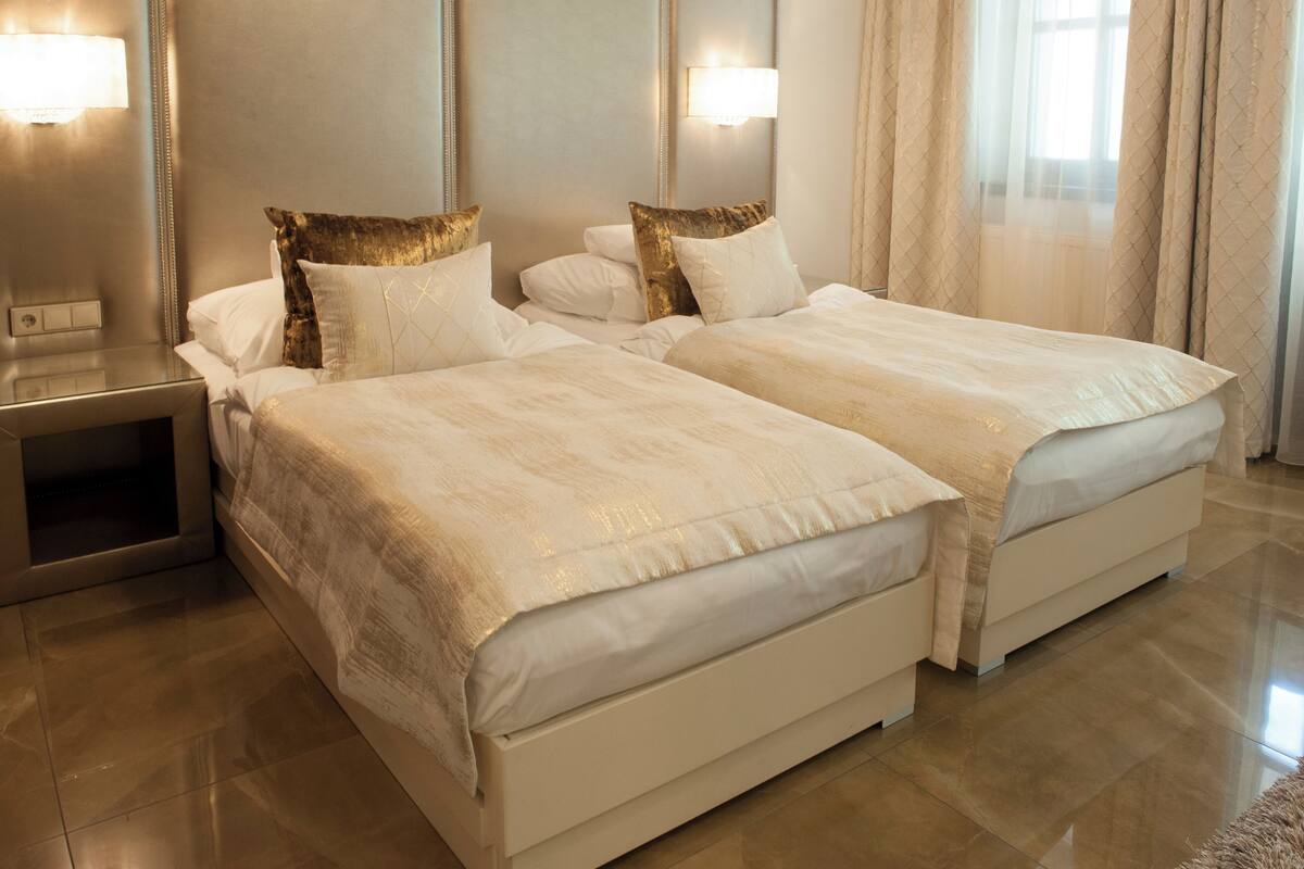 A hotel room with two beds, a nightstand, and a mirror.