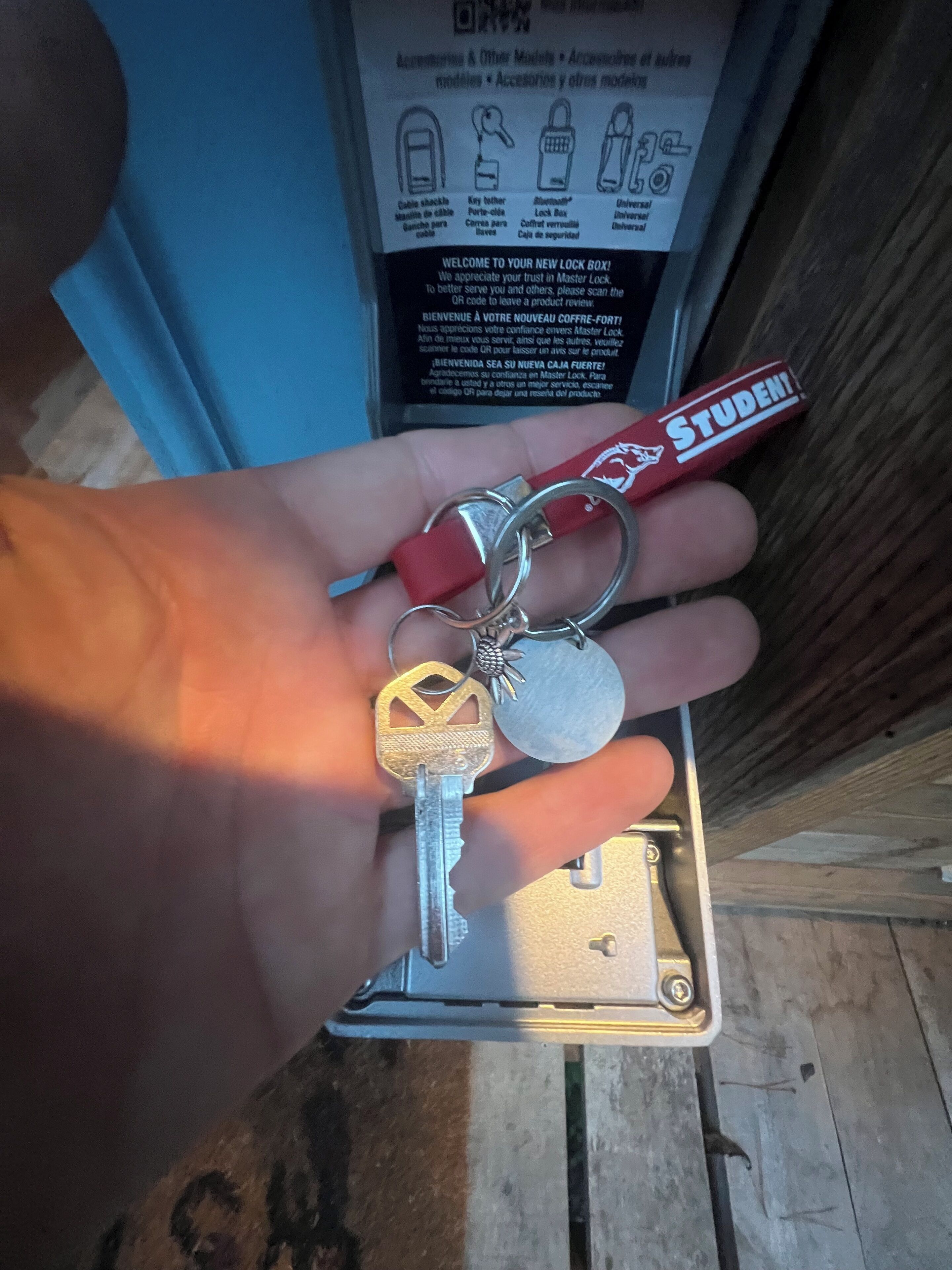 A hand holding a set of keys with a keychain and a red tag labeled "STUDENTI".