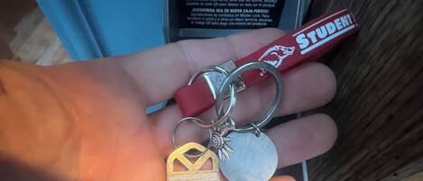 A hand holding a set of keys with a keychain and a red tag labeled "STUDENTI".