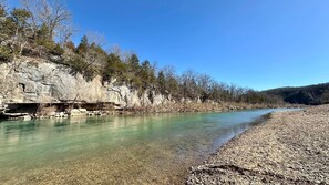 A river with clear water, rocky banks, and trees.