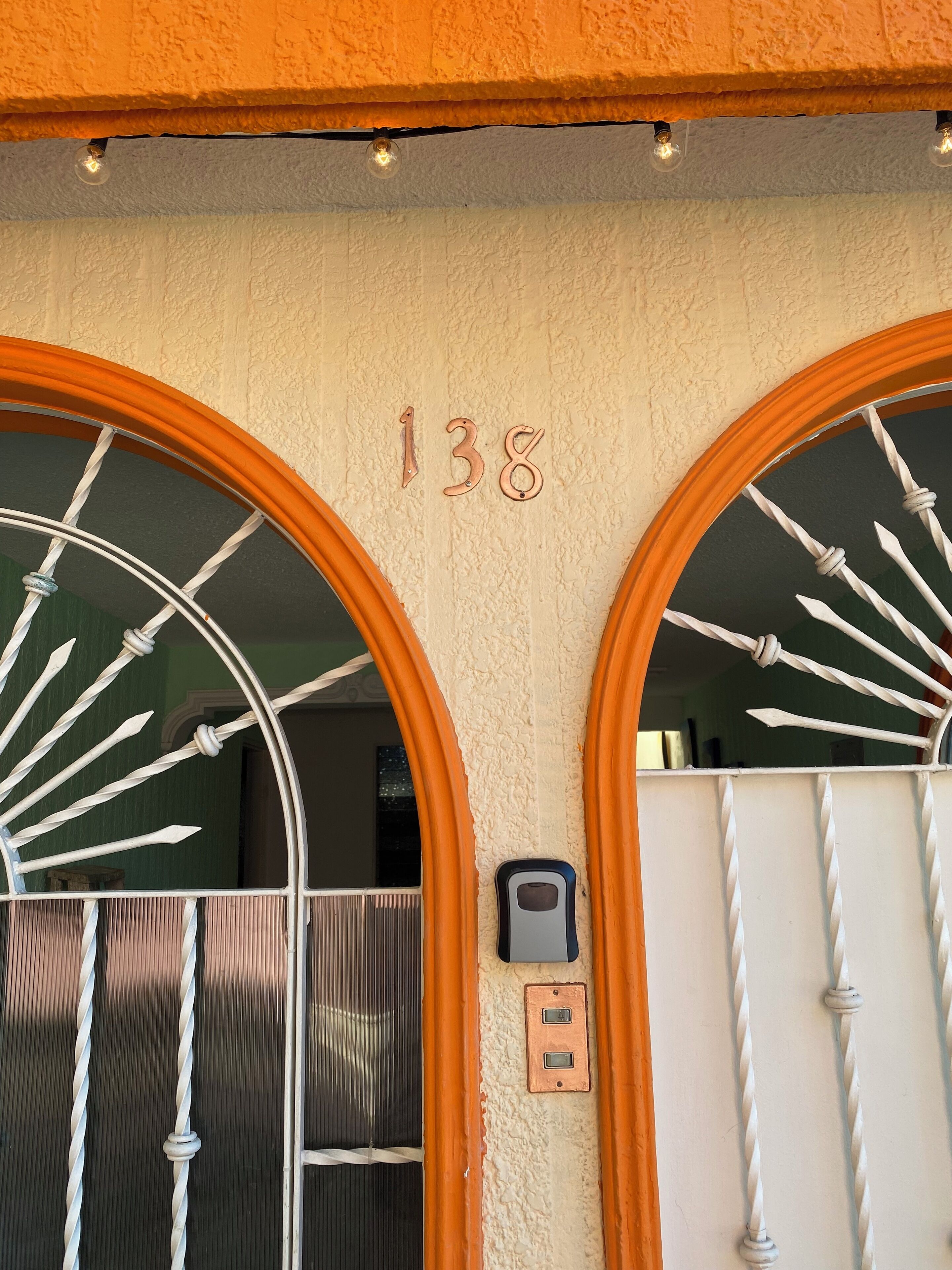 A building entrance with two large arched windows, a number '138' above the windows, and a security keypad below.