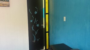 A room with a bed, a door with a decorative design, and an air conditioning unit. - Casa Vacacional Canoa 138 (La Paz)