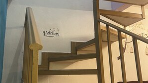 A wooden staircase with a 'Welcome' sign, a framed artwork on the wall, and a small table at the bottom. - Casa Vacacional Canoa 138 (La Paz)