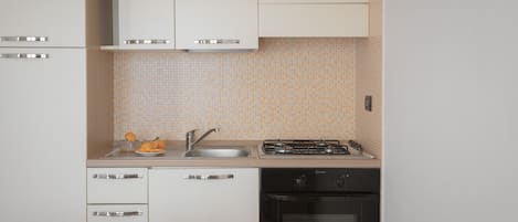 A compact kitchen with white cabinets, a sink, a stove, and a dishwasher.