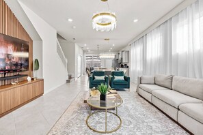 Ein modernes Wohnzimmer mit einer Couch, einem Couchtisch und einem Fernseher auf einer Holzkommode.