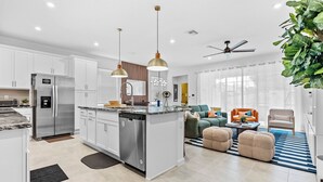 Una cocina moderna con electrodomésticos de acero inoxidable, iluminación colgante y una isla central.