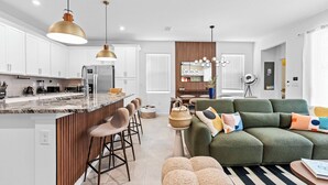 Una cocina moderna con armarios blancos, encimera de granito y una isla central con taburetes de bar.