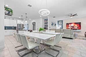 A modern kitchen with white cabinets, stainless steel appliances, and a dining area with a white table and chairs. - 7BR house sleeps 17 with private pool in kissimmee (Kissimmee)