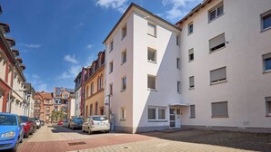 A street view with a row of buildings, including a white building with a sloped roof and multiple windows. - Cosima - Kaiserslautern (Kaiserslautern)