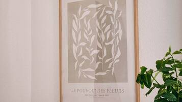 A framed artwork titled 'GALERIE D'ART' with a floral design, placed above a dining table with plates, cutlery, and a glass of water.