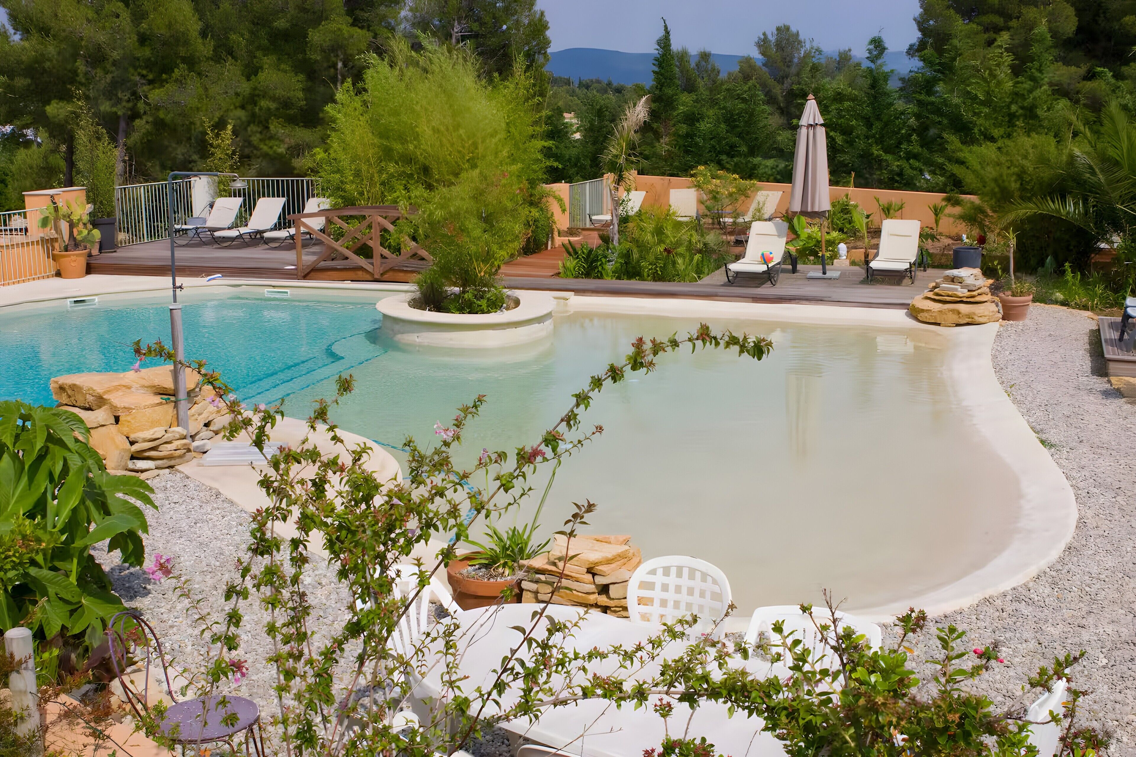 A swimming pool with lounge chairs, a deck area, and surrounding greenery.