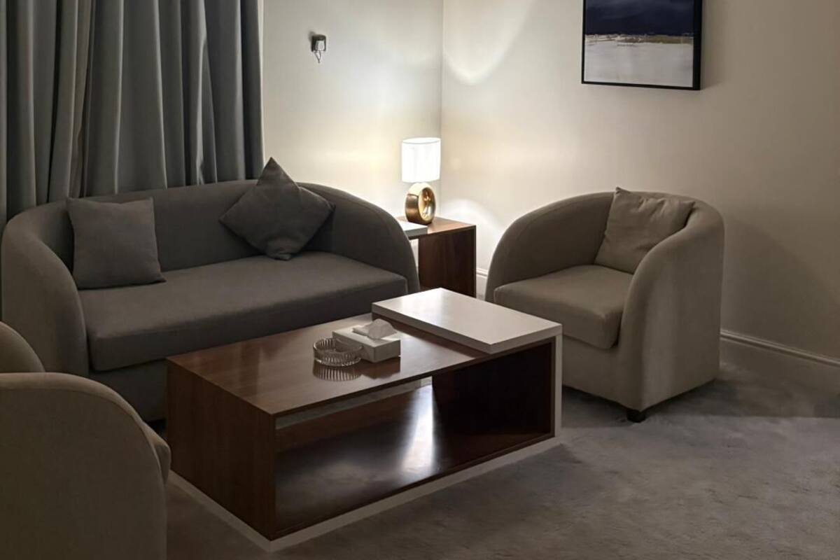 A modern living room with a grey sofa, a beige armchair, and a wooden coffee table.