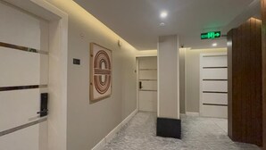 A hallway with a marble floor, a framed artwork on the wall, and a door with a handle. - DIFFERENT HOTEL (Tabuk)