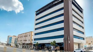 A modern hotel with a prominent 'ATKUZ' sign, featuring multiple floors and a central entrance. - DIFFERENT HOTEL (Tabuk)
