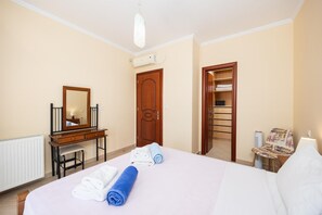 Quarto de hotel com cama, escrivaninha com espelho, guarda-roupa e uma cadeira.