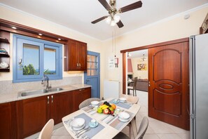 A modern kitchen with wooden cabinets, a built-in sink, and a dining area with a table set for two.