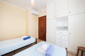 Habitación de hotel con dos camas, un armario y un equipo de aire acondicionado.