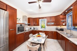 Cozinha moderna com armários de madeira, eletrodomésticos de aço inoxidável e um espaço de jantar com mesa posta para dois.