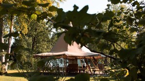 A rustic outdoor pavilion with a conical roof, surrounded by trees and grass. - Cozy 6-person Lodge by the Fishing Pond (Balkbrug)