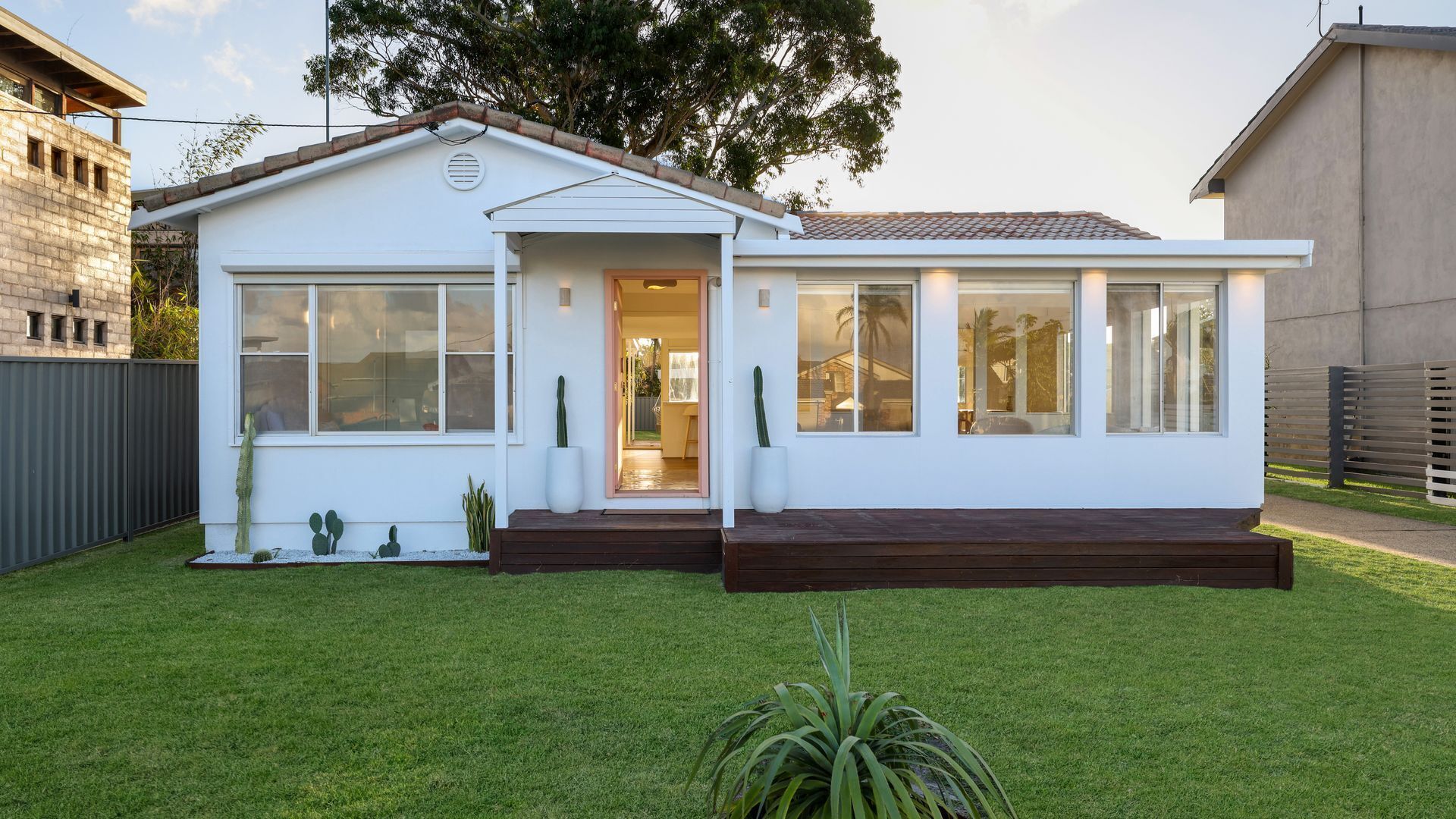 A modern single-story house with a white exterior, large windows, and a well-maintained lawn.