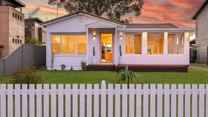 Une maison moderne à deux étages, dotée d’une pelouse bien entretenue et d’une clôture blanche en bois.