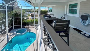 A covered outdoor area with a pool, a table, and a chair. - Tropical Hideaway - Three Bedroom House, Sleeps 8 (Fort Myers Beach)