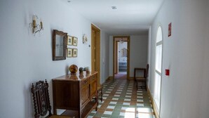 A hallway with a checkered floor, wooden furniture, a mirror, and framed pictures on the wall. - Casa Pizarro Hotel (Cáceres)