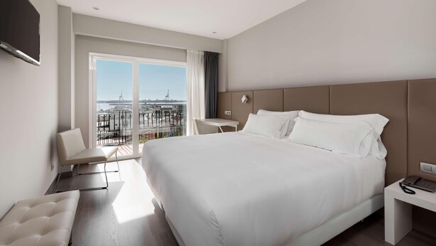 A modern hotel room with a large bed, a desk, and a chair. - Silken Turcosa 3 Sup (Castelló de la Plana)