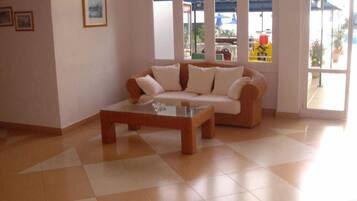 Una sala de estar con sofá, una mesa de centro, ventanas amplias y vistas al exterior.
