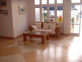 Una sala de estar con sofá, una mesa de centro, ventanas amplias y vistas al exterior.