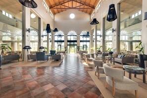 A spacious lobby with a high ceiling, large windows, and modern furniture. - Barcelo Costa Ballena Golf & Spa (Rota)